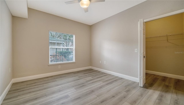 unfurnished bedroom with a closet, ceiling fan, a walk in closet, and light hardwood / wood-style floors