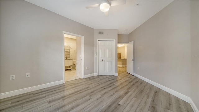 unfurnished bedroom with ceiling fan, ensuite bathroom, and light hardwood / wood-style flooring