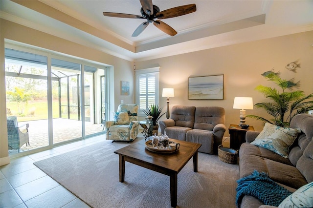 tiled living room featuring a raised ceiling, ceiling fan, and crown molding