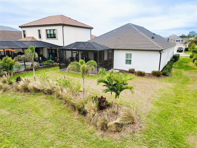 rear view of property with glass enclosure and a lawn