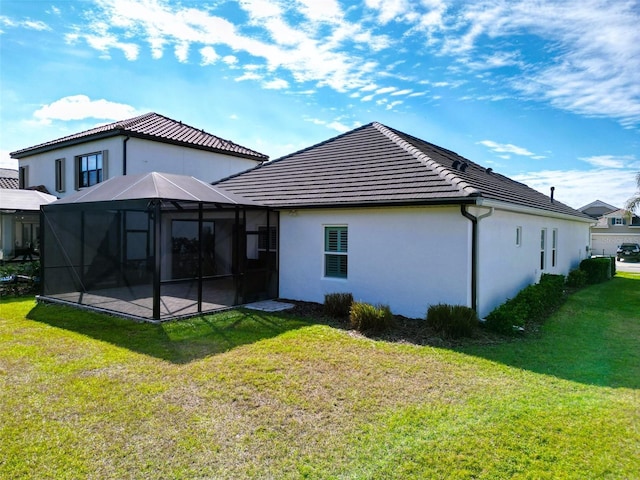 rear view of house with glass enclosure and a lawn