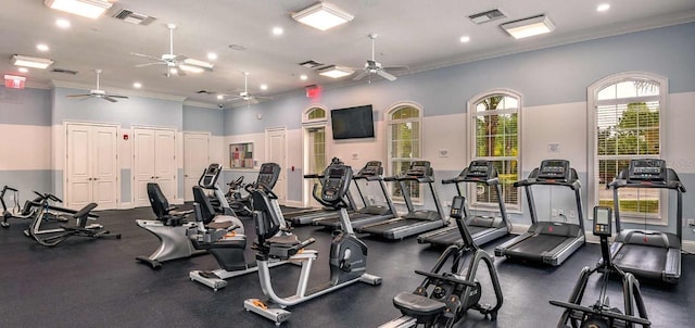 exercise room featuring ceiling fan, ornamental molding, and a towering ceiling