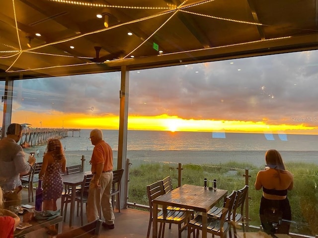 patio terrace at dusk featuring a water view and a view of the beach