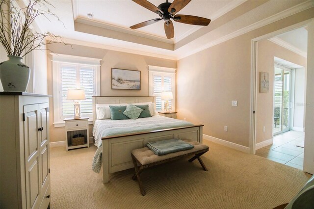 carpeted bedroom featuring ceiling fan, access to outside, crown molding, and a tray ceiling