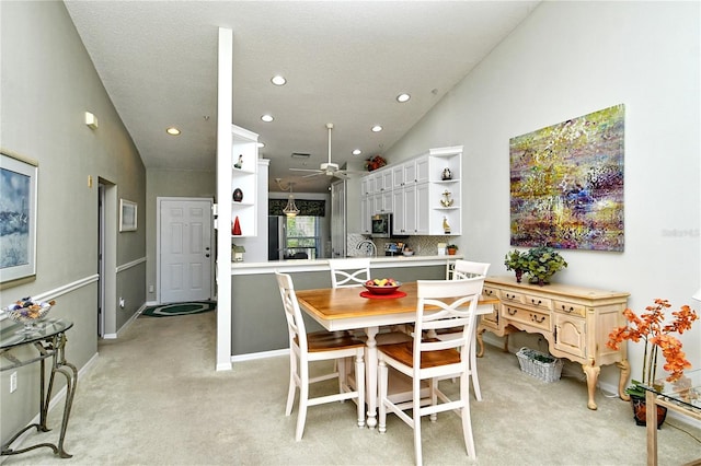 dining area with ceiling fan, high vaulted ceiling, and light carpet