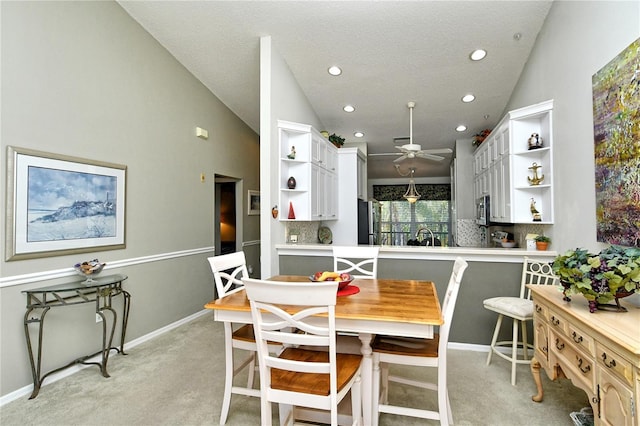 dining area featuring ceiling fan, light colored carpet, lofted ceiling, and sink