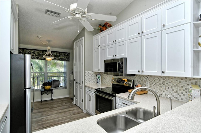 kitchen featuring white cabinets, stainless steel appliances, vaulted ceiling, and sink