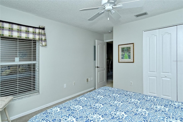 carpeted bedroom with ceiling fan, a textured ceiling, and a closet