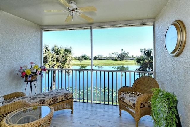 sunroom with a wealth of natural light, a water view, and ceiling fan