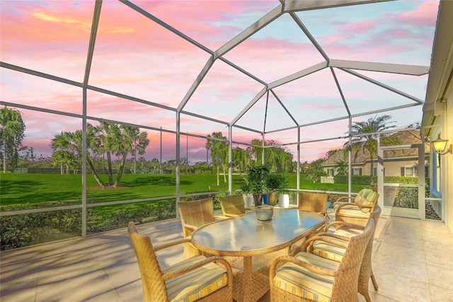 patio terrace at dusk featuring a yard and glass enclosure