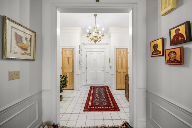 hall featuring a notable chandelier, light tile patterned floors, and crown molding