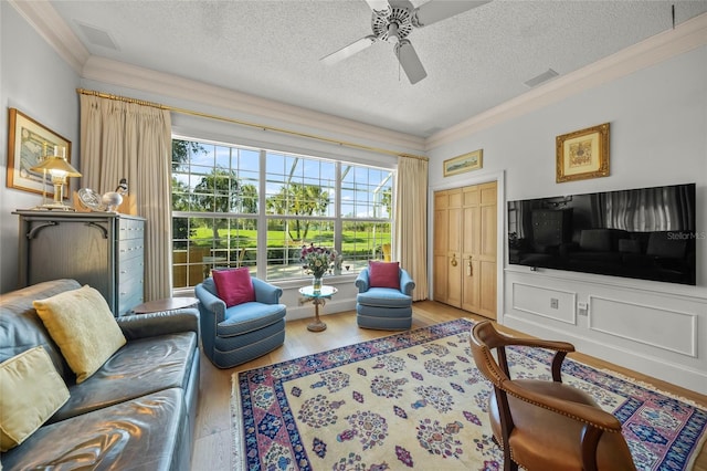 living room with a textured ceiling, hardwood / wood-style floors, ceiling fan, and ornamental molding