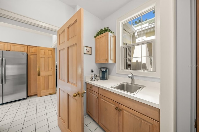 kitchen featuring stainless steel refrigerator, light tile patterned floors, and sink