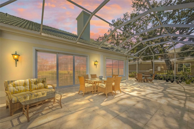 patio terrace at dusk featuring glass enclosure and an outdoor living space