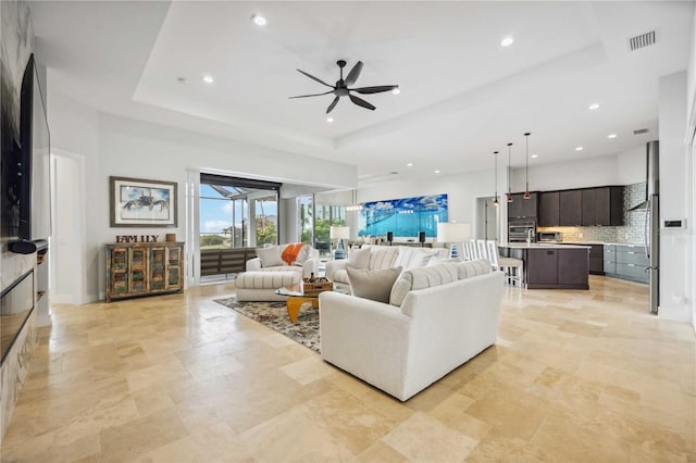 living room featuring ceiling fan and a raised ceiling