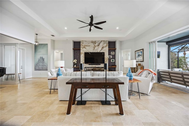 living room with a raised ceiling and ceiling fan