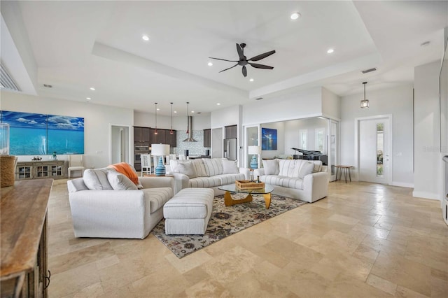 living room featuring ceiling fan, a towering ceiling, and a tray ceiling