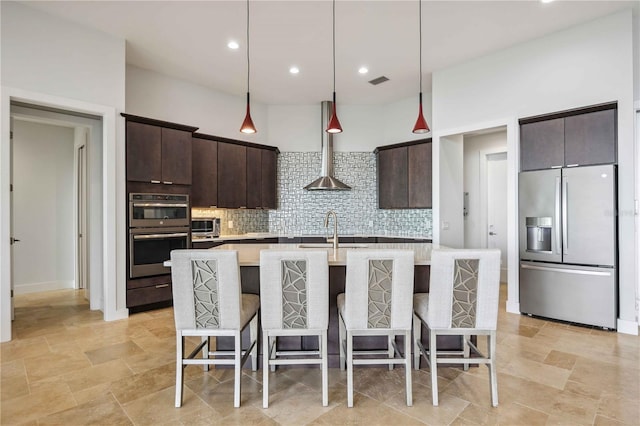 kitchen with appliances with stainless steel finishes, a center island with sink, a breakfast bar area, and dark brown cabinetry