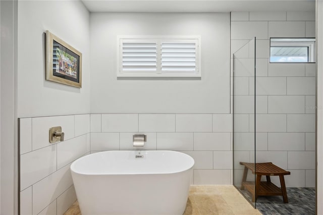 bathroom featuring shower with separate bathtub and tile walls