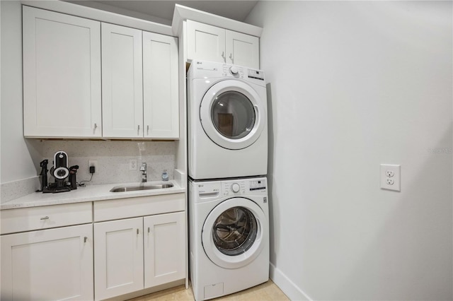 clothes washing area with sink, cabinets, and stacked washer / dryer