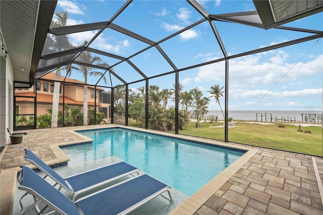 view of swimming pool featuring a yard, a patio area, glass enclosure, and a water view