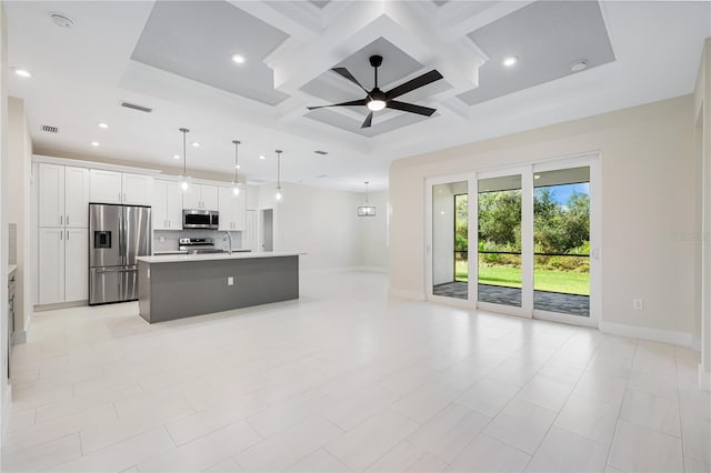 kitchen with coffered ceiling, appliances with stainless steel finishes, an island with sink, pendant lighting, and white cabinets