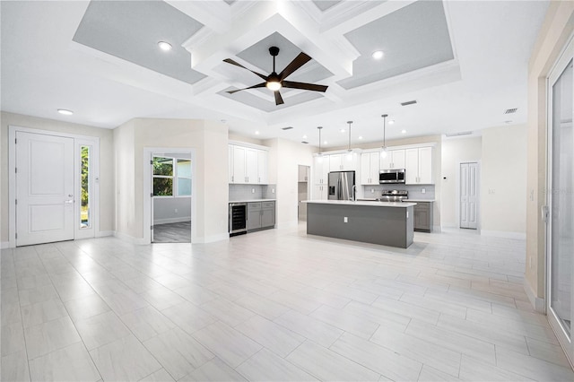 unfurnished living room featuring beverage cooler, beam ceiling, ceiling fan, ornamental molding, and coffered ceiling