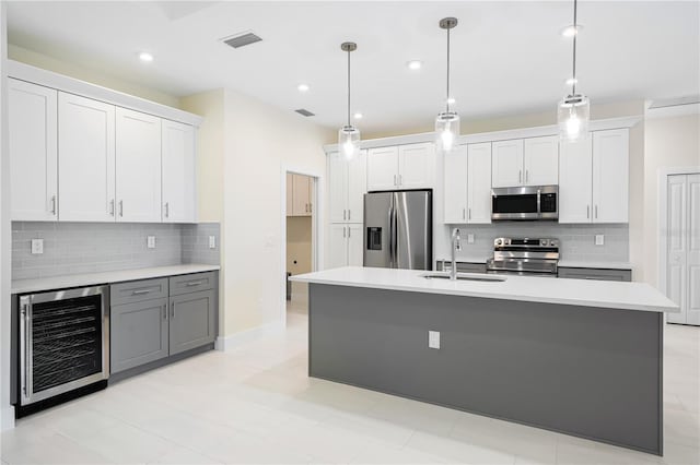 kitchen featuring pendant lighting, stainless steel appliances, wine cooler, white cabinetry, and sink