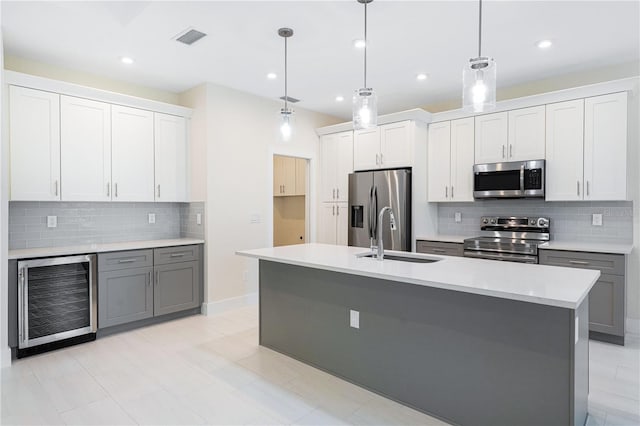 kitchen featuring hanging light fixtures, stainless steel appliances, beverage cooler, gray cabinetry, and white cabinets