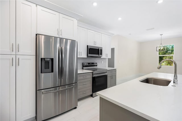 kitchen with sink, white cabinets, decorative backsplash, gray cabinets, and appliances with stainless steel finishes