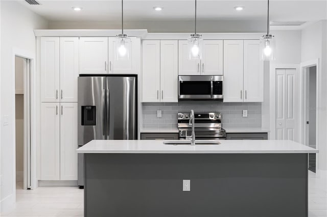 kitchen featuring appliances with stainless steel finishes, white cabinets, and a kitchen island with sink