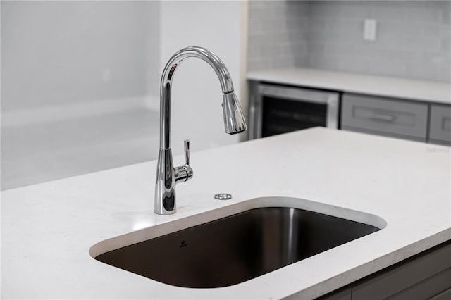 room details featuring beverage cooler, gray cabinetry, and sink