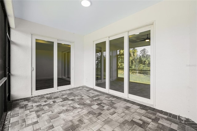 unfurnished sunroom featuring ceiling fan