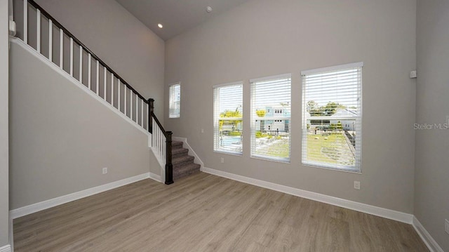 unfurnished living room featuring high vaulted ceiling and light hardwood / wood-style flooring