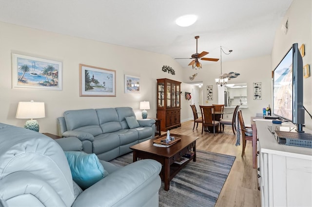 living room with ceiling fan, vaulted ceiling, and light wood-type flooring