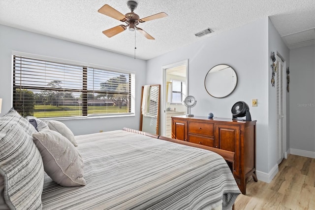 bedroom with a textured ceiling, ceiling fan, and light hardwood / wood-style floors