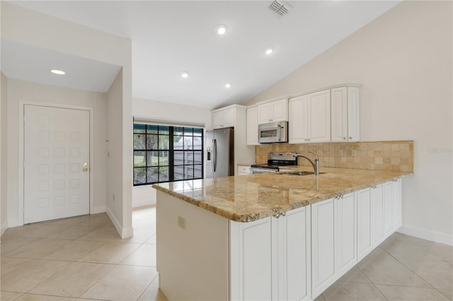 kitchen with appliances with stainless steel finishes, kitchen peninsula, sink, and light stone countertops