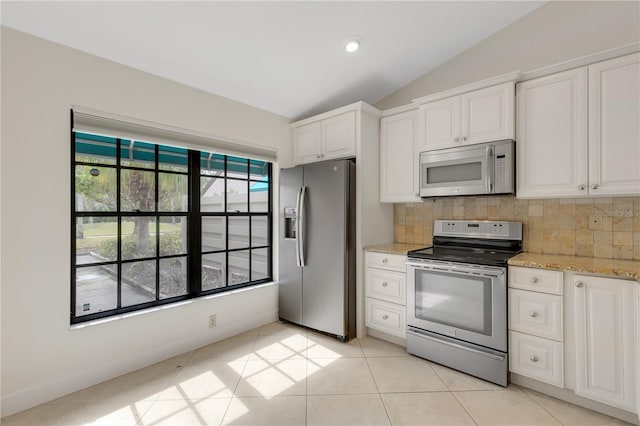kitchen featuring appliances with stainless steel finishes, tasteful backsplash, lofted ceiling, white cabinets, and light stone countertops
