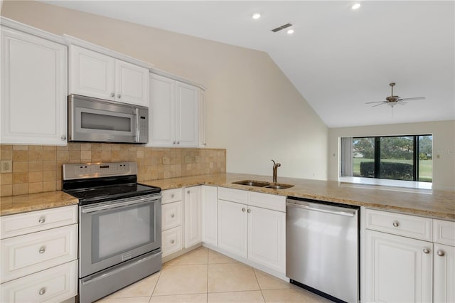 kitchen featuring lofted ceiling, light tile patterned floors, white cabinetry, stainless steel appliances, and kitchen peninsula