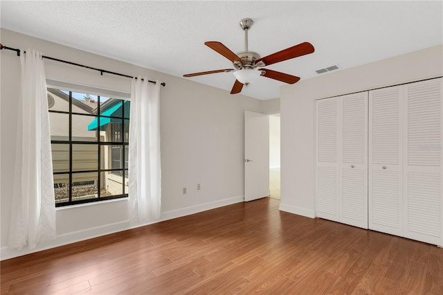 unfurnished bedroom featuring hardwood / wood-style flooring, ceiling fan, a textured ceiling, and a closet