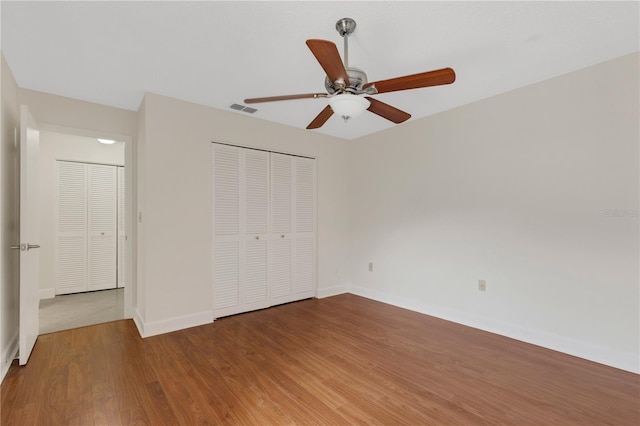 unfurnished bedroom with wood-type flooring, ceiling fan, and a closet