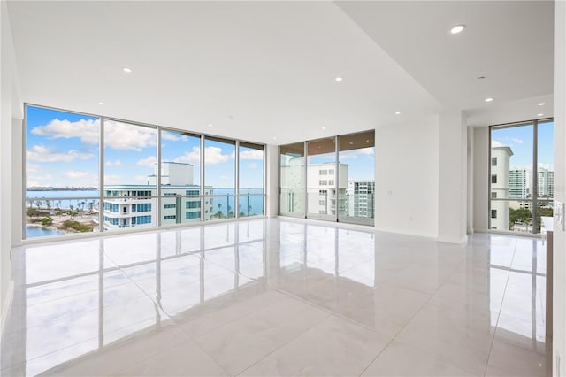 tiled empty room with expansive windows and a water view