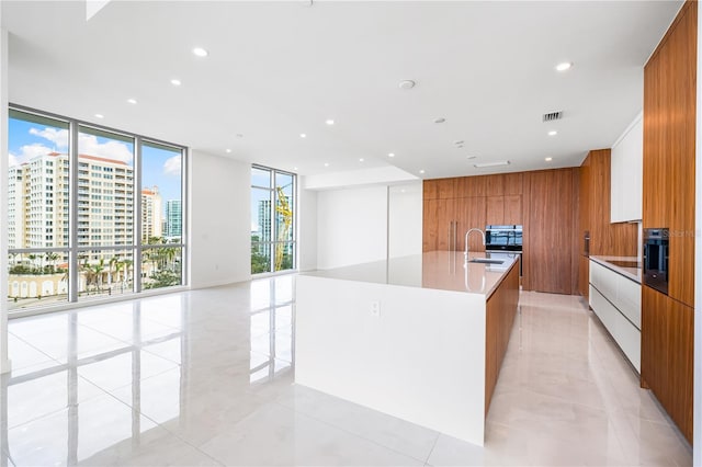 111 Golden Gate Pt Unit 701Ph, Sarasota, FL 34236 - kitchen featuring a large island with sink, floor to ceiling windows, visible vents, modern cabinets, and brown cabinetry