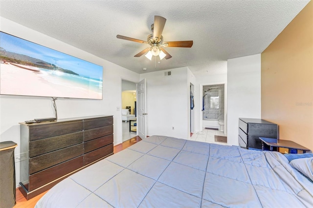 bedroom with a textured ceiling, ensuite bathroom, and ceiling fan