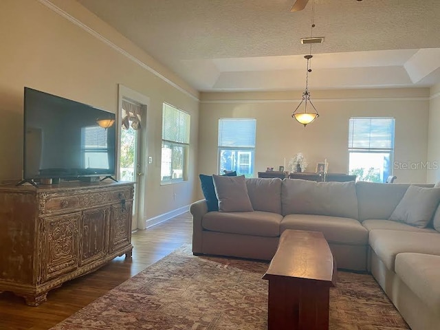 living room with a textured ceiling, ceiling fan, a raised ceiling, and dark wood-type flooring