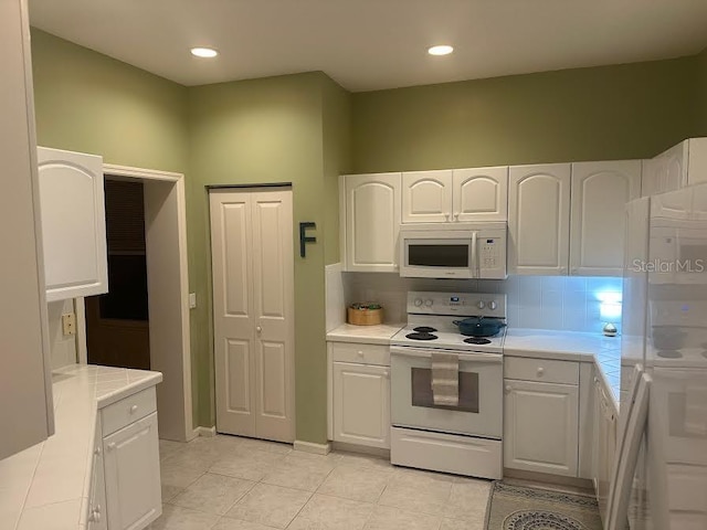 kitchen featuring white cabinetry, white appliances, and light tile patterned floors