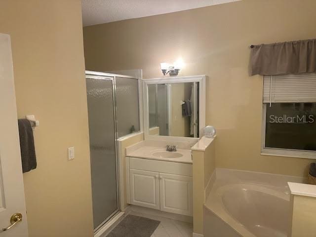 bathroom featuring plus walk in shower, vanity, and tile patterned flooring