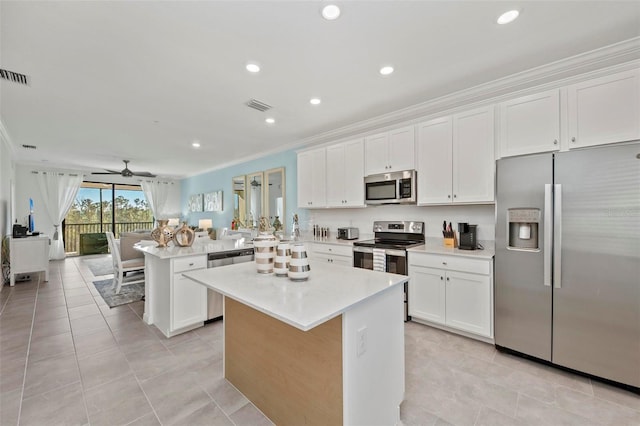 kitchen featuring white cabinets, appliances with stainless steel finishes, ceiling fan, and a center island