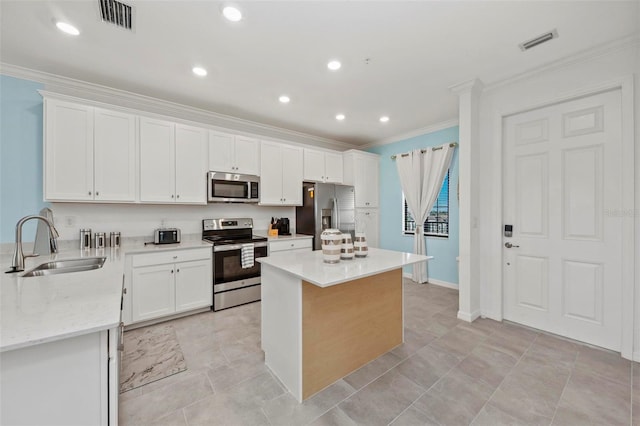 kitchen featuring light stone countertops, stainless steel appliances, a kitchen island, white cabinetry, and sink