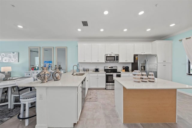 kitchen featuring stainless steel appliances, white cabinets, sink, and a large island